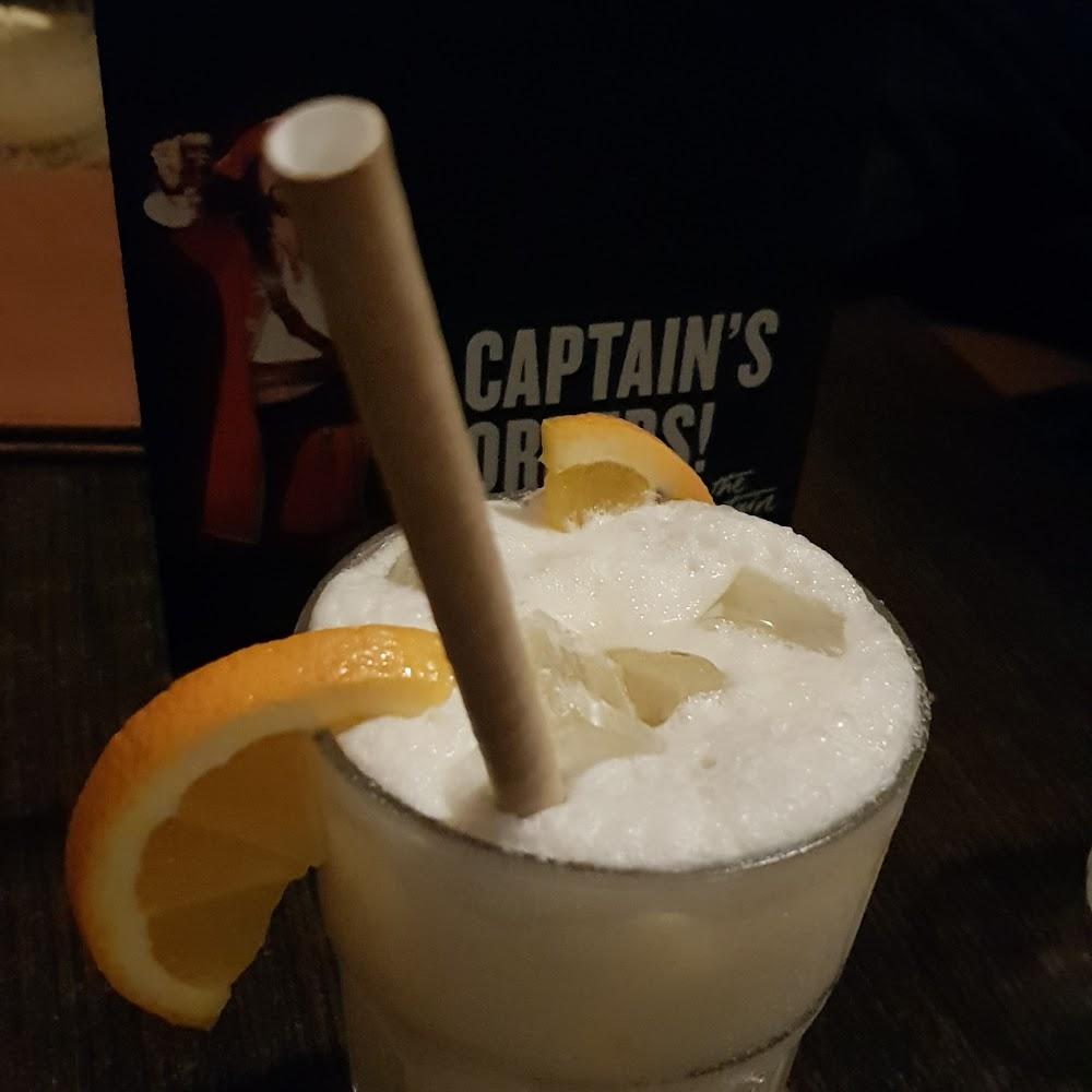 A white cocktail with an orange slice and a straw.
